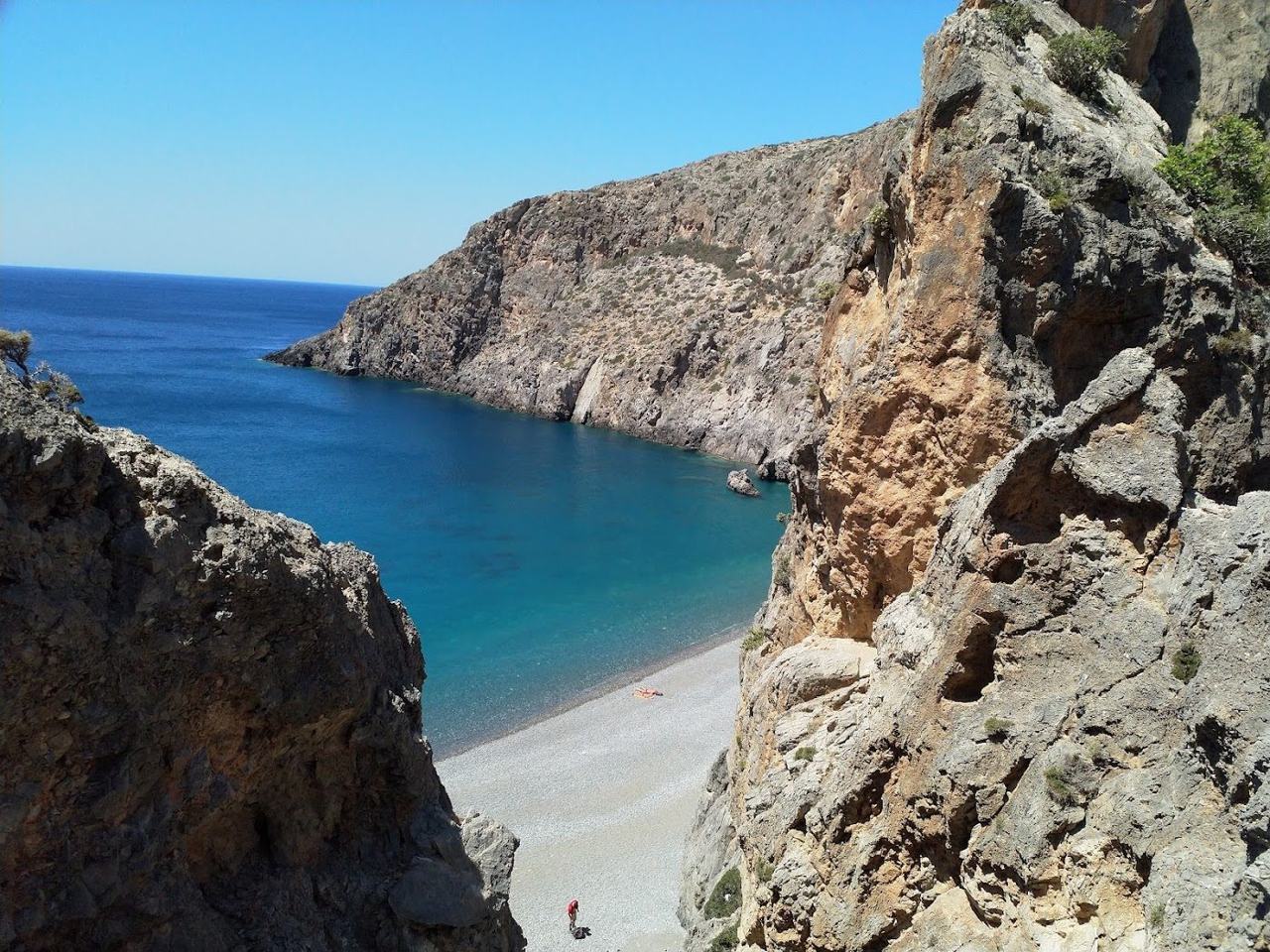 Pebble cove and deep blue sea framed by tall cliffs at the mouth of the Agiofarago gorge on the south coast of Crete
