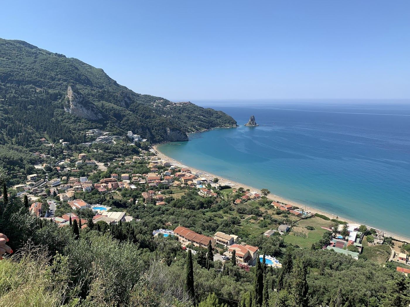 Long golden sand and the Ortholithi rock at Agios Gordios beach in Corfu