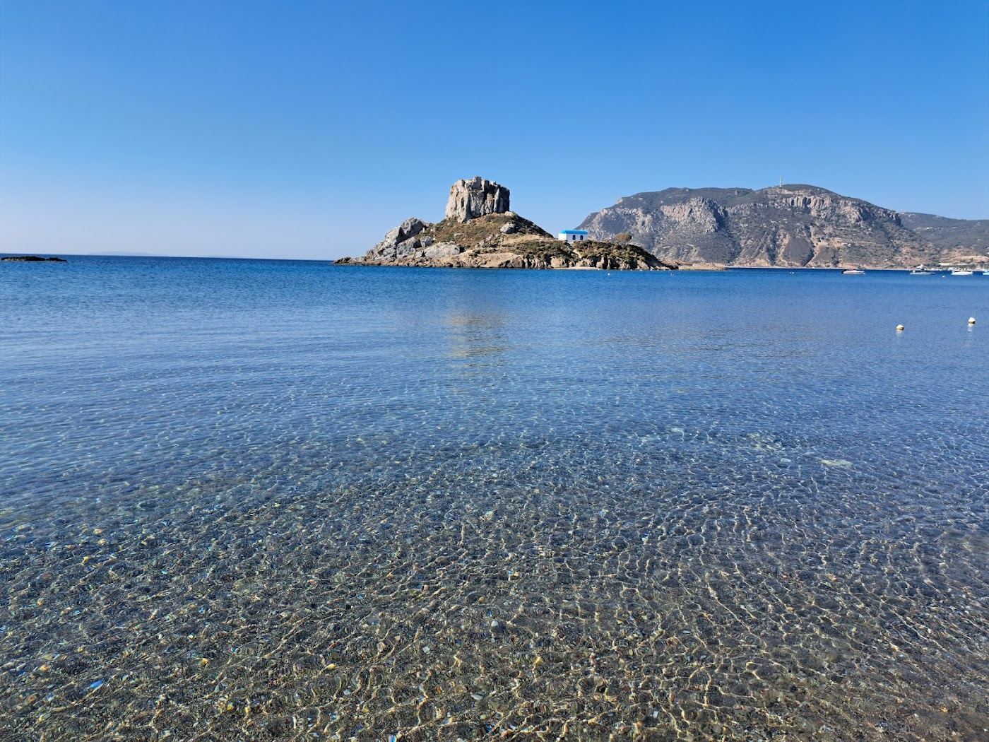 Clear shallow water and the Kastri islet seen from Agios Stefanos beach in Kos