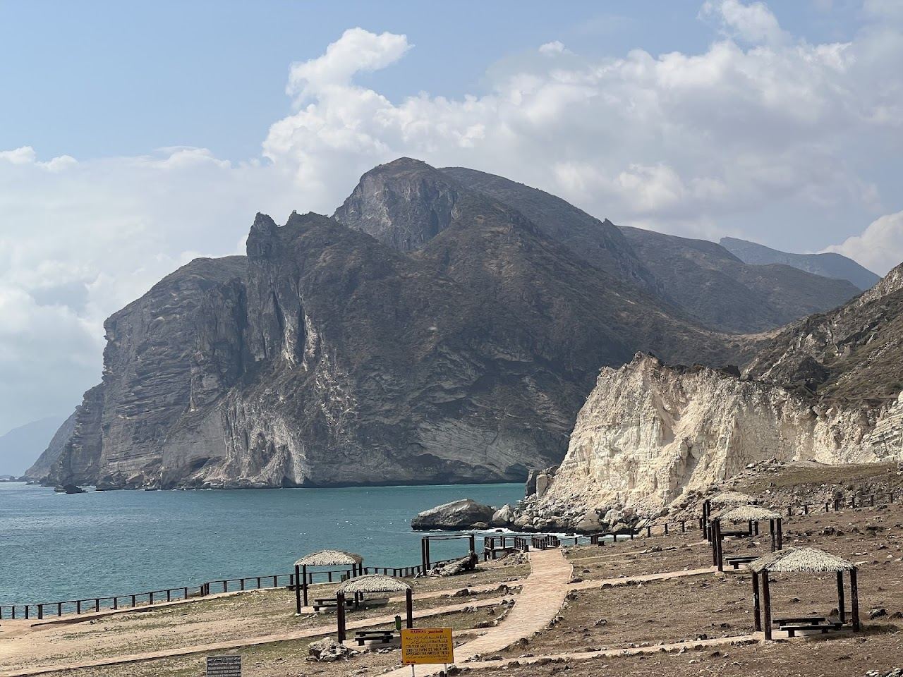 Pale sand below tall cliffs and a wide bay at Al Mughsail beach near Salalah in Oman