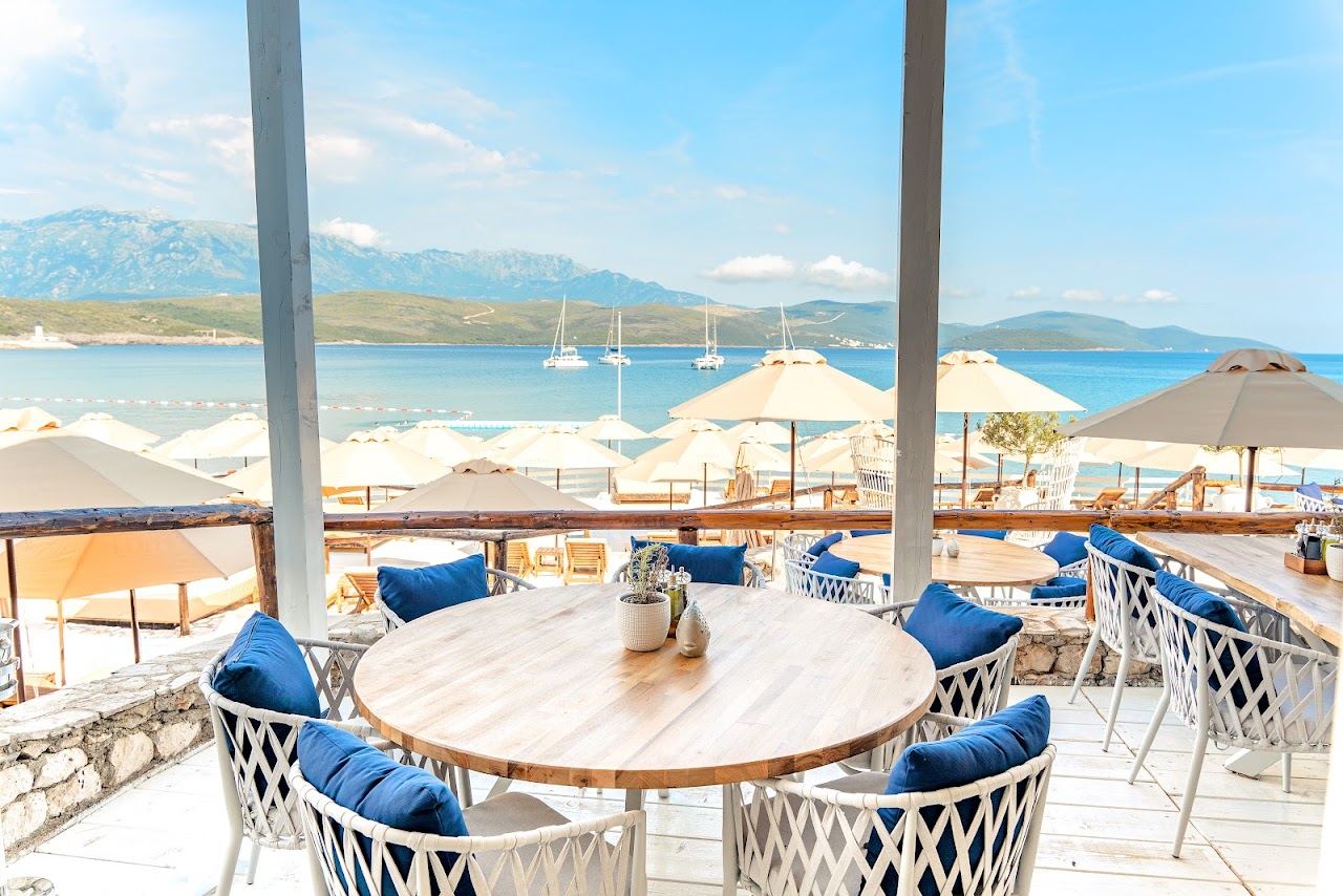 Ivory umbrellas and sunbed rows of Almara Beach Club above the pebble cove at Oblatno