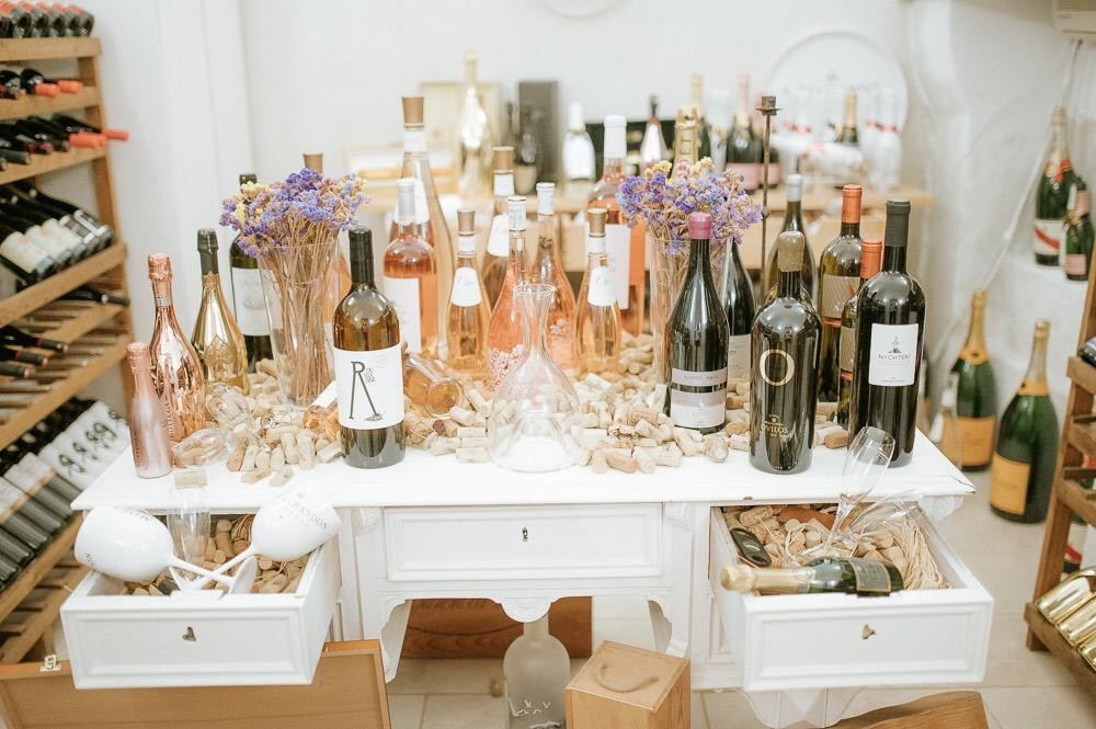Wine and champagne bottles arranged over a white desk and corks in the stone cellar at Almyra Seaside