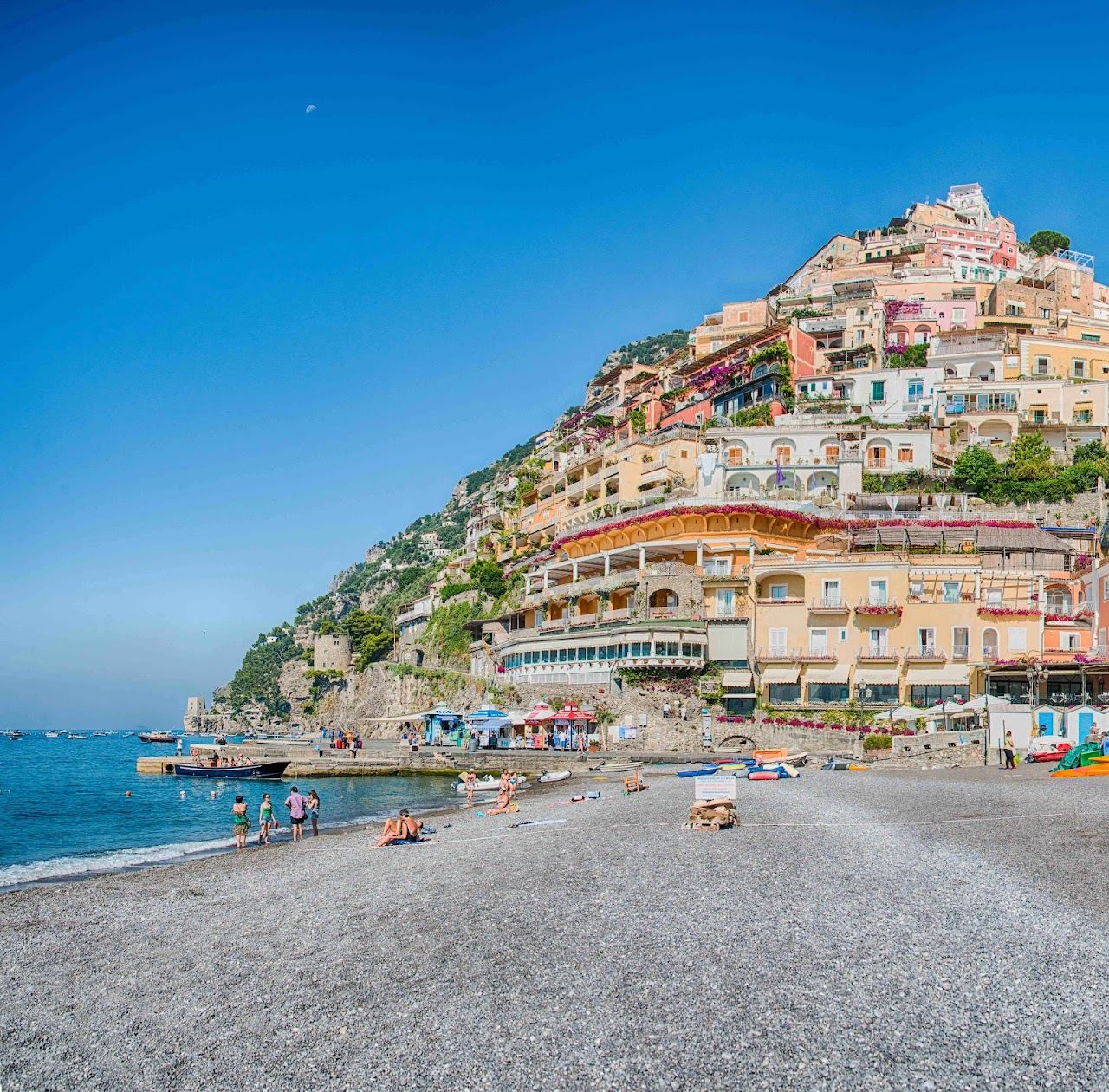 Pastel cliffside houses above a pebbly beach and turquoise sea at Positano on the Amalfi Coast in Italy