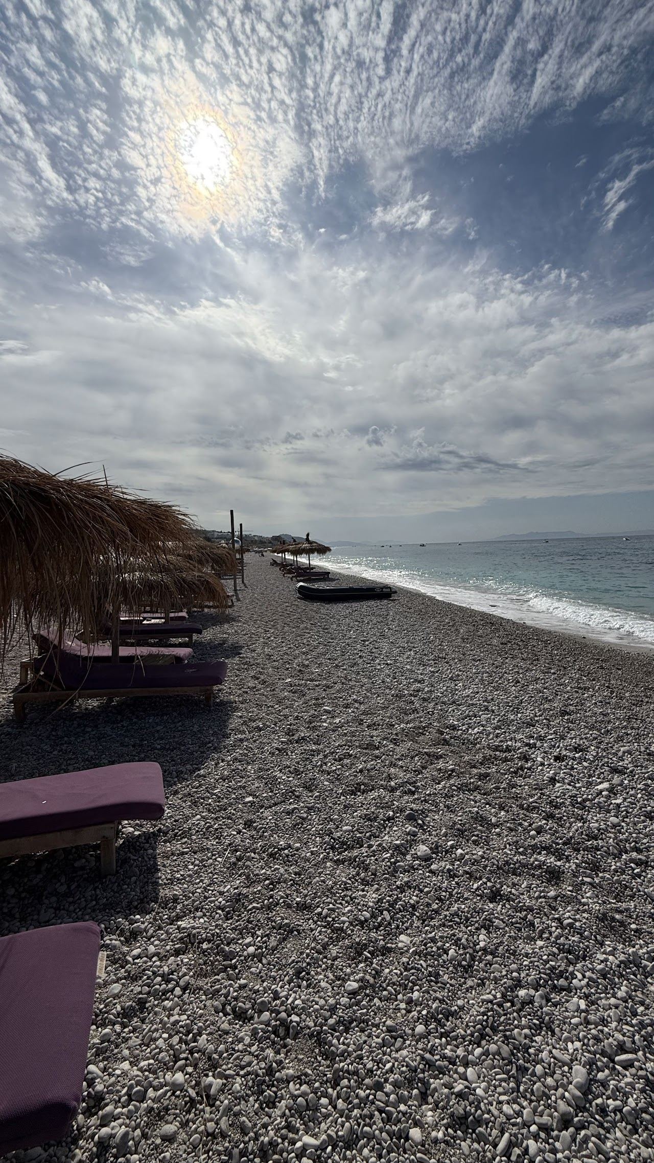 The white pebble shore and clear turquoise water of Drymades beach at Dhermi below the mountains