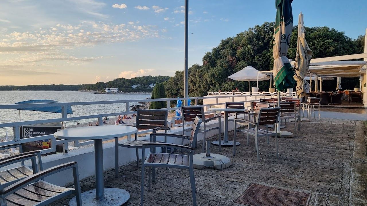 Beach bar and loungers on the pebble at Ambrela beach on the Verudela peninsula near Pula