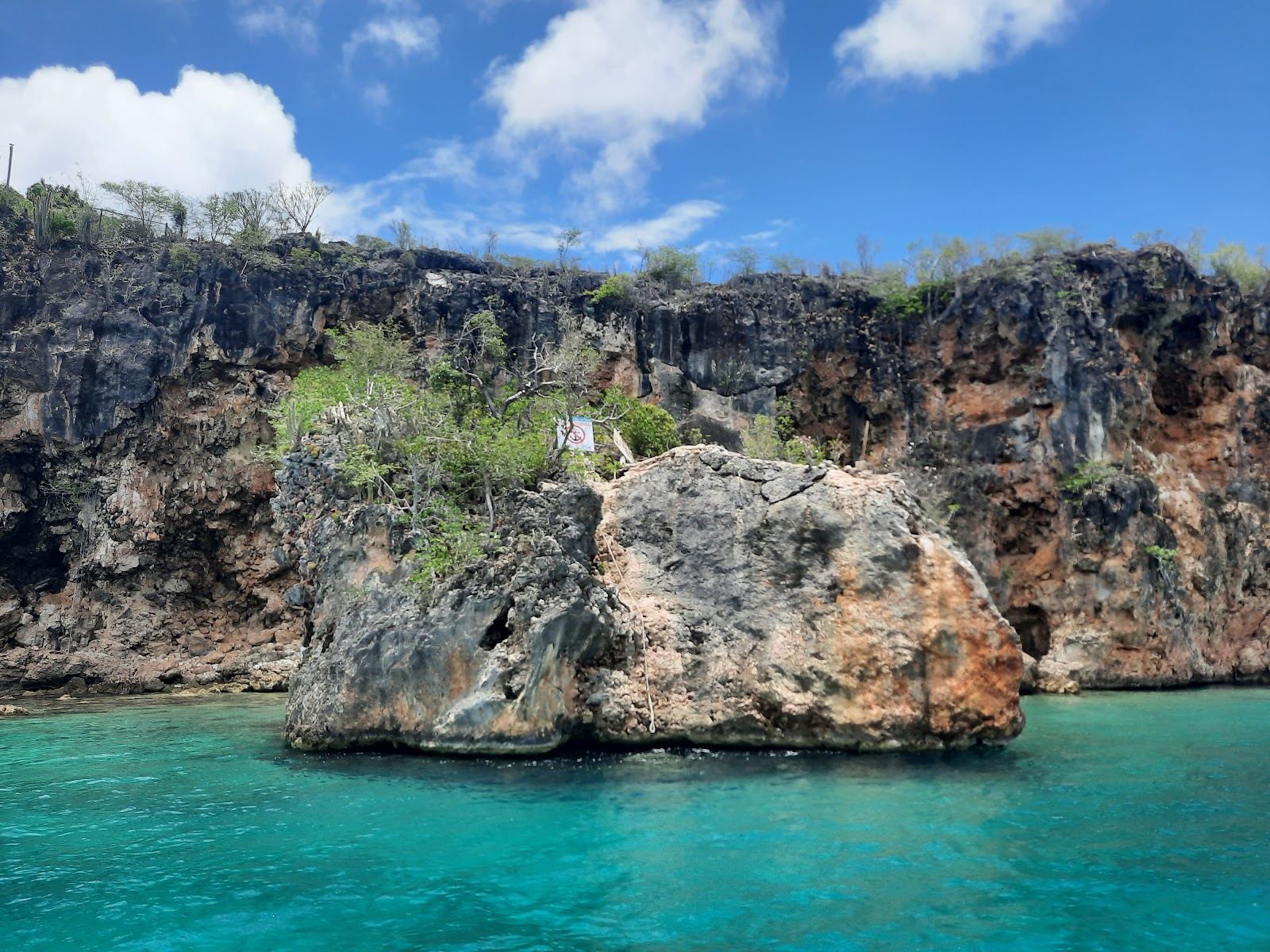 A tiny pocket of pale sand and clear sheltered water at the foot of cliffs at Little Bay in Anguilla