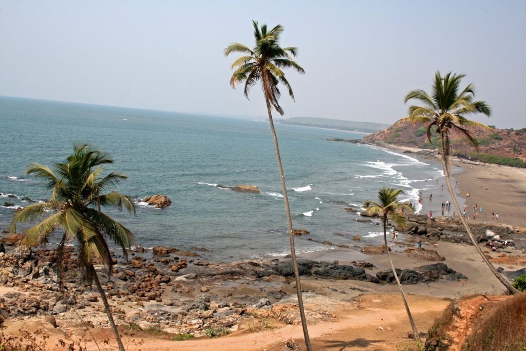 Rocky red cliffs above the sand at Anjuna Beach in north Goa