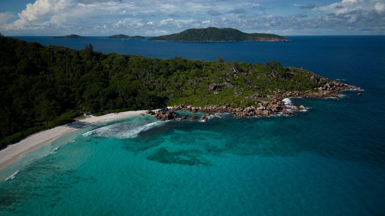 Wide pale sand, granite boulders and open surf at Anse Cocos on the east coast of La Digue in Seychelles