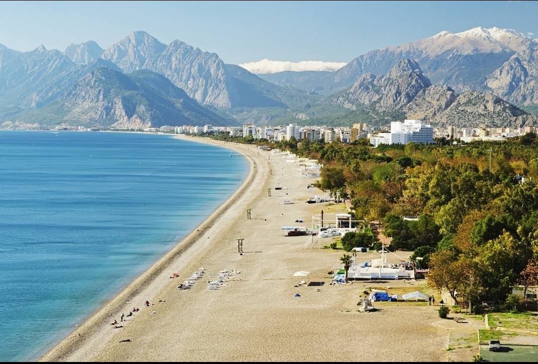 The long city beach at Konyaalti in Antalya below the Beydaglari mountains with a beach park behind the sand
