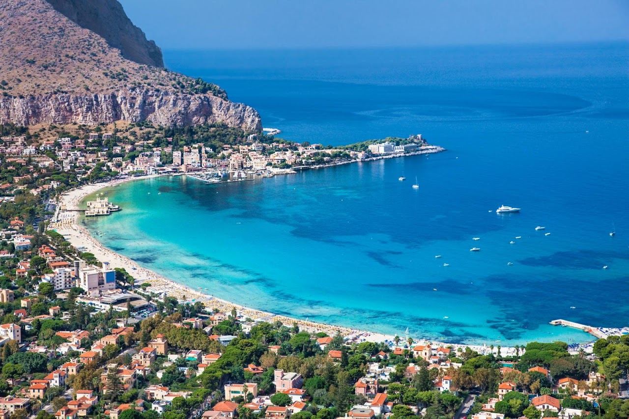 White sand and shallow turquoise water in the bay at Mondello beneath Monte Pellegrino