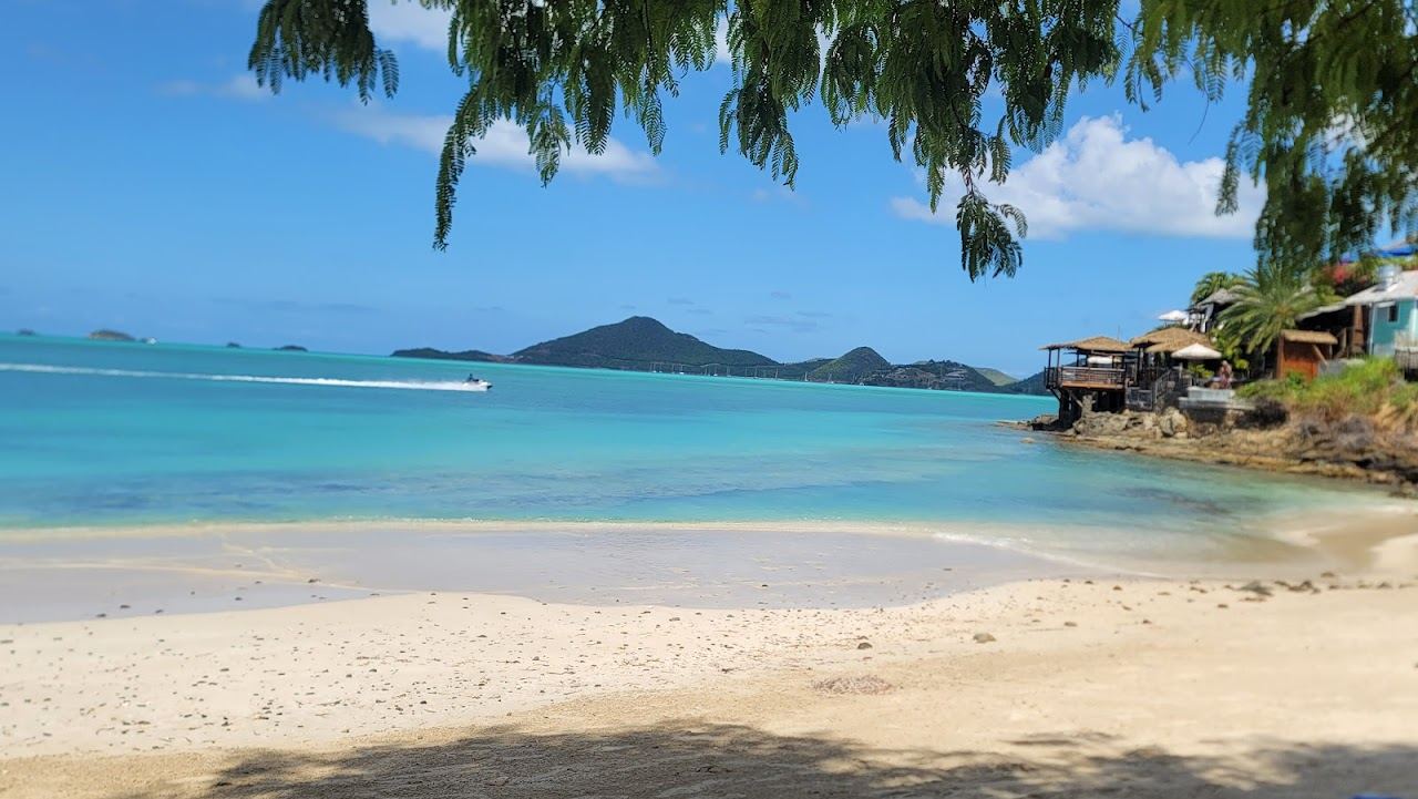 Golden sand and calm Caribbean water with a beach bar at sunset on Ffryes Beach in Antigua
