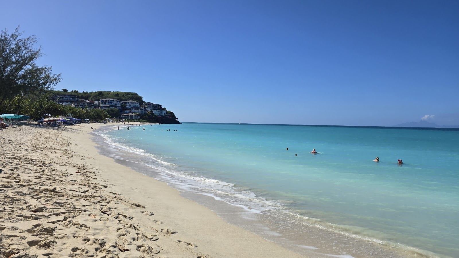 Warm evening light over calm turquoise water and pale sand on the west coast of Antigua