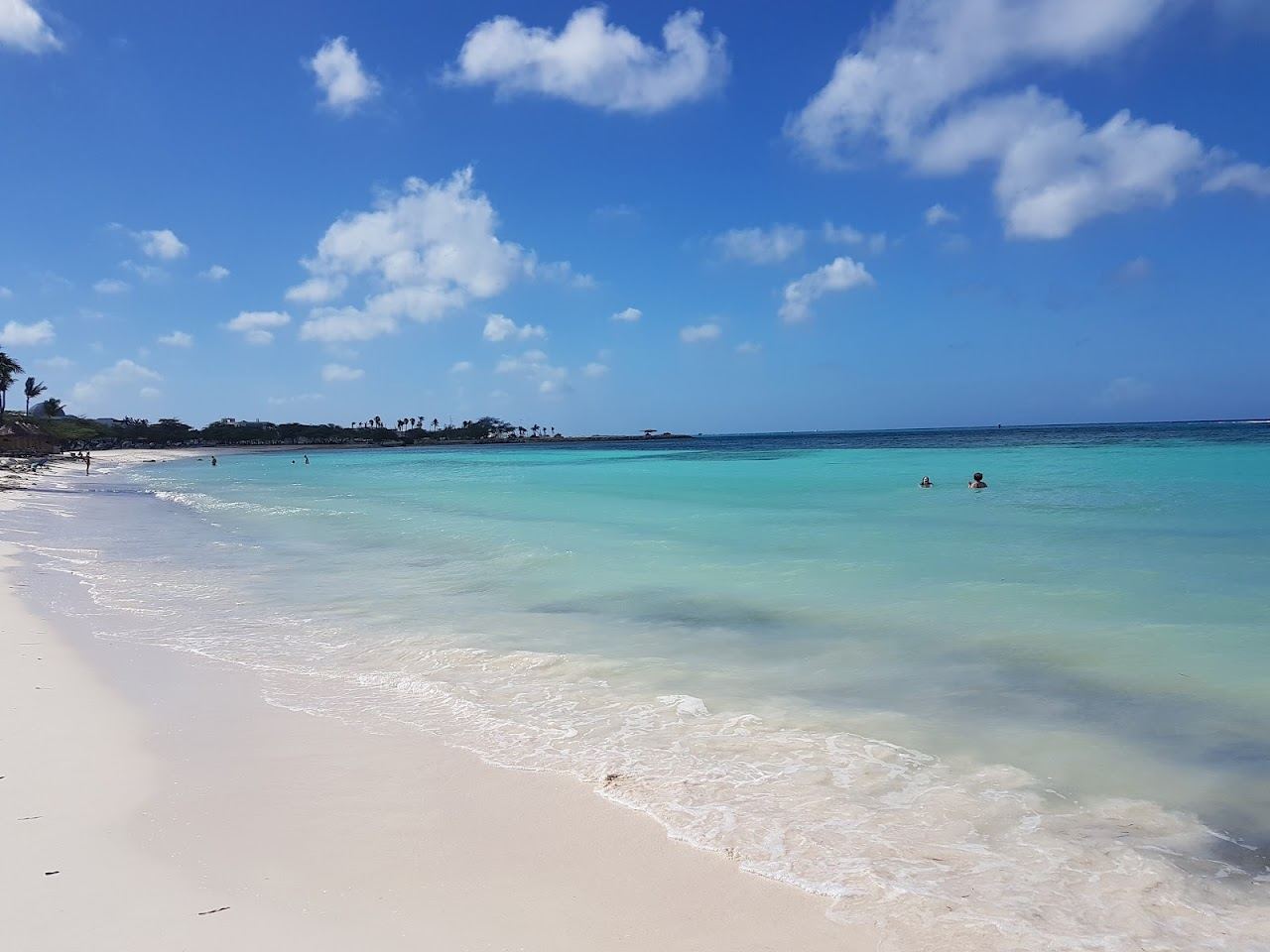 Calm clear water and soft white sand backed by low rise resorts at Druif Beach in Aruba