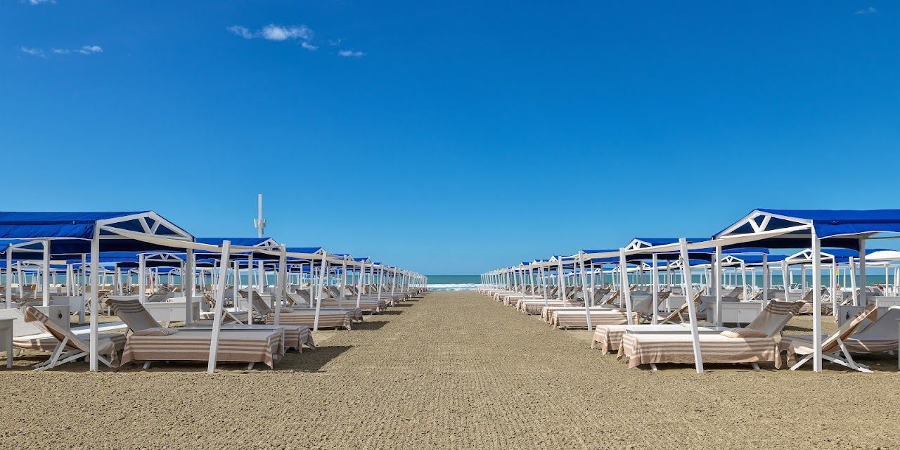 Ordered rows of furnished gazebo tents on the raked sand at Augustus Beach Club in Forte dei Marmi