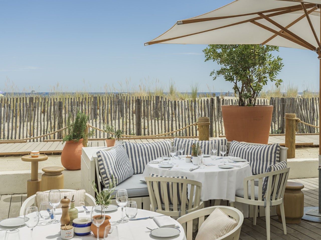 Set lunch tables and white parasols on the terrace at Bagatelle on Pampelonne beach near Saint Tropez