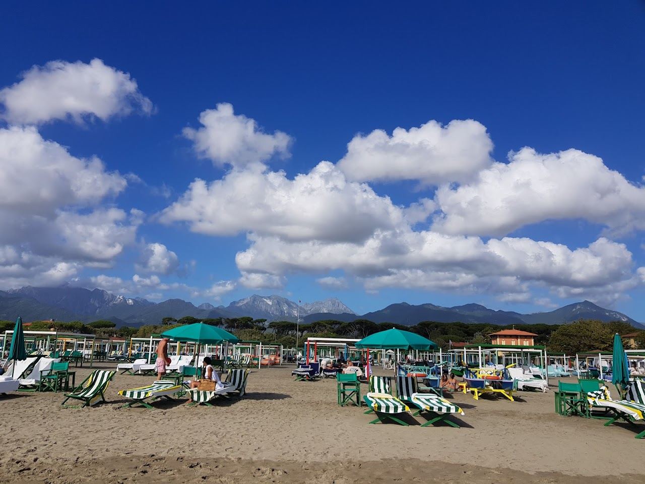 Rows of tents and loungers on the sand at Bagno Piero in Forte dei Marmi with the Apuan Alps behind