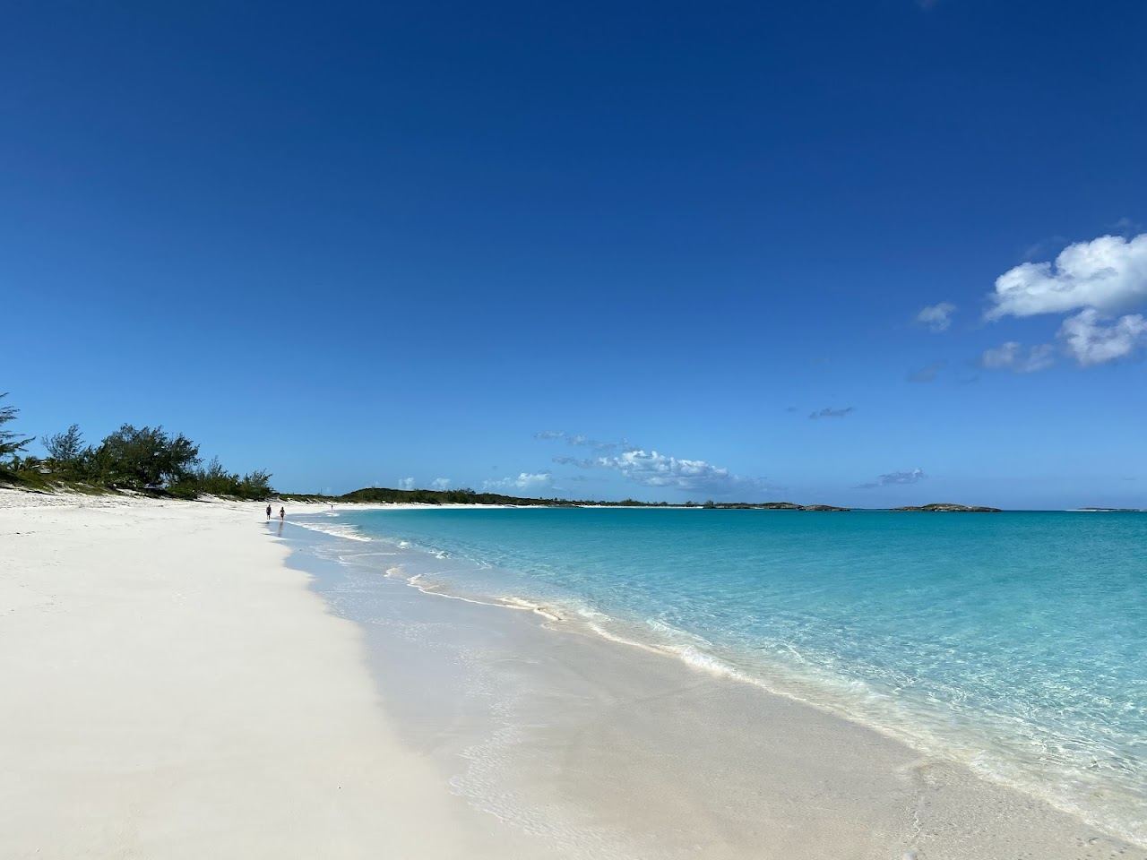 Long, near empty white sand crescent and calm turquoise water at Tropic of Cancer Beach on Little Exuma in the Bahamas