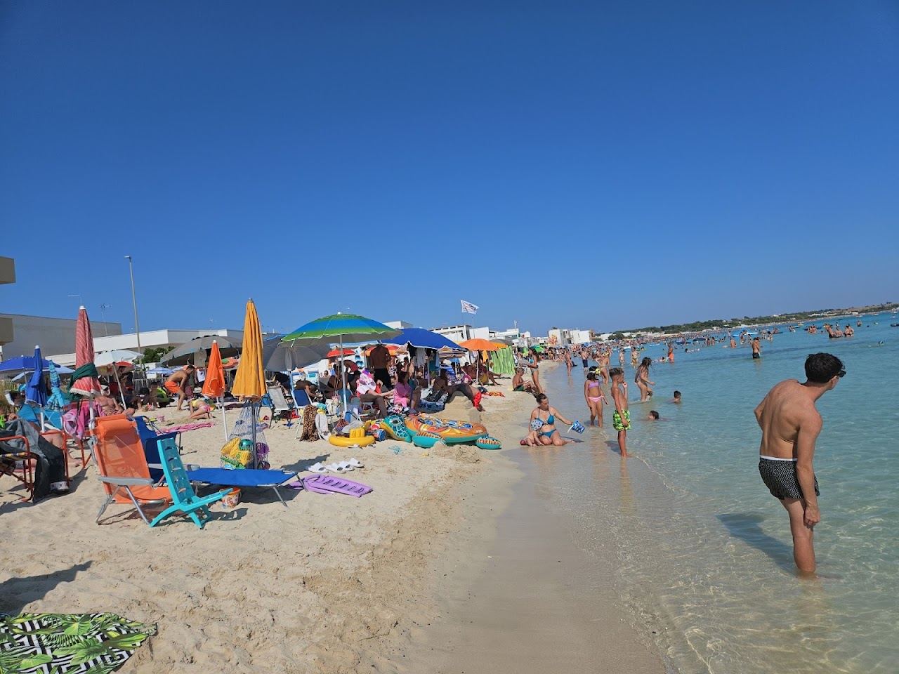 Shallow turquoise water over pale sand along the Torre Lapillo beach near Porto Cesareo in the Salento