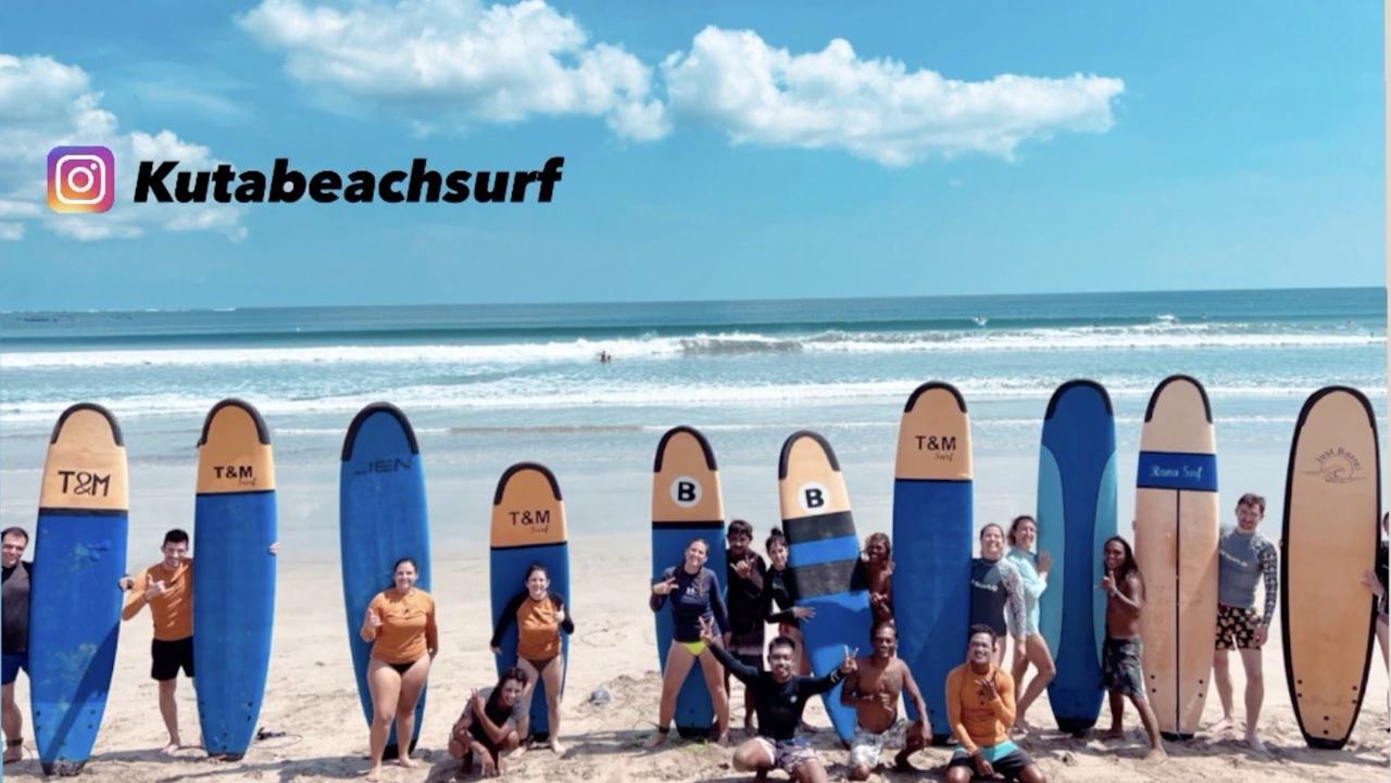 Beginner surfers carrying soft boards into the white water at Kuta beach Bali