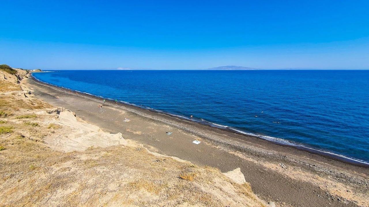 The quiet shoreline and tamarisk shade at Baxedes Beach near Oia