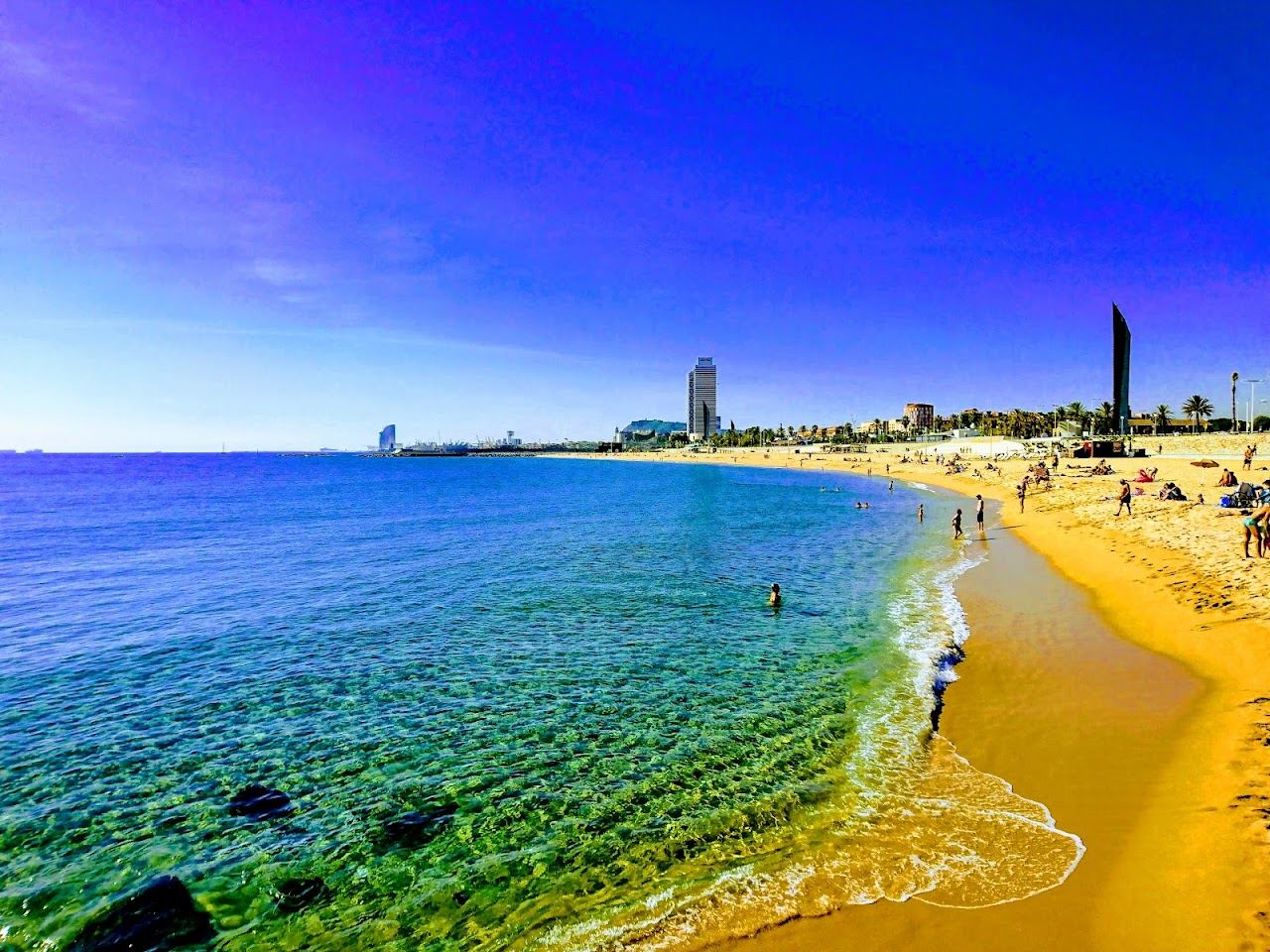 Clean wide sand and calm blue water at Bogatell beach in Barcelona on a sunny day