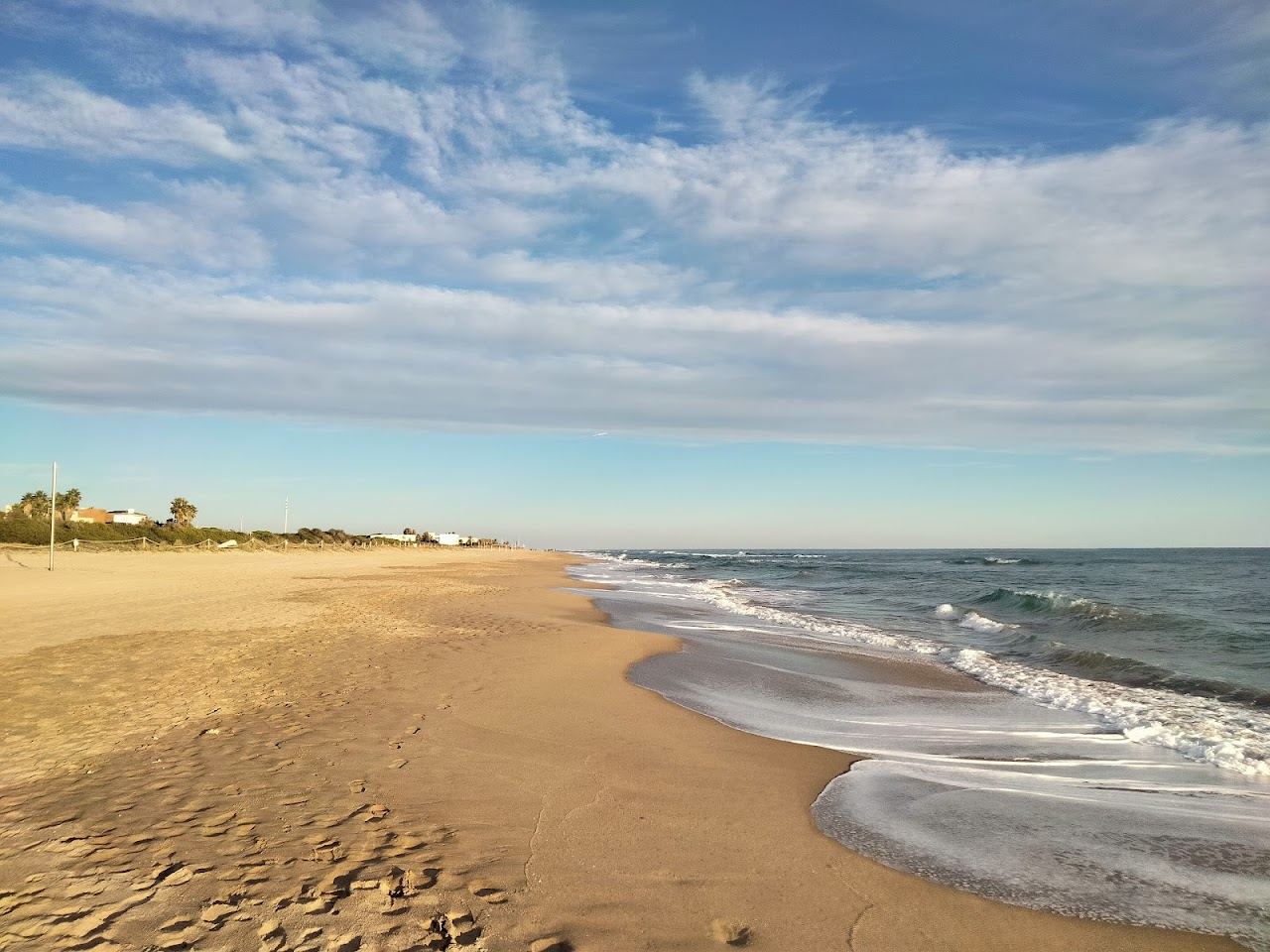 A long wide open beach of pale sand and blue sea at Castelldefels south of Barcelona
