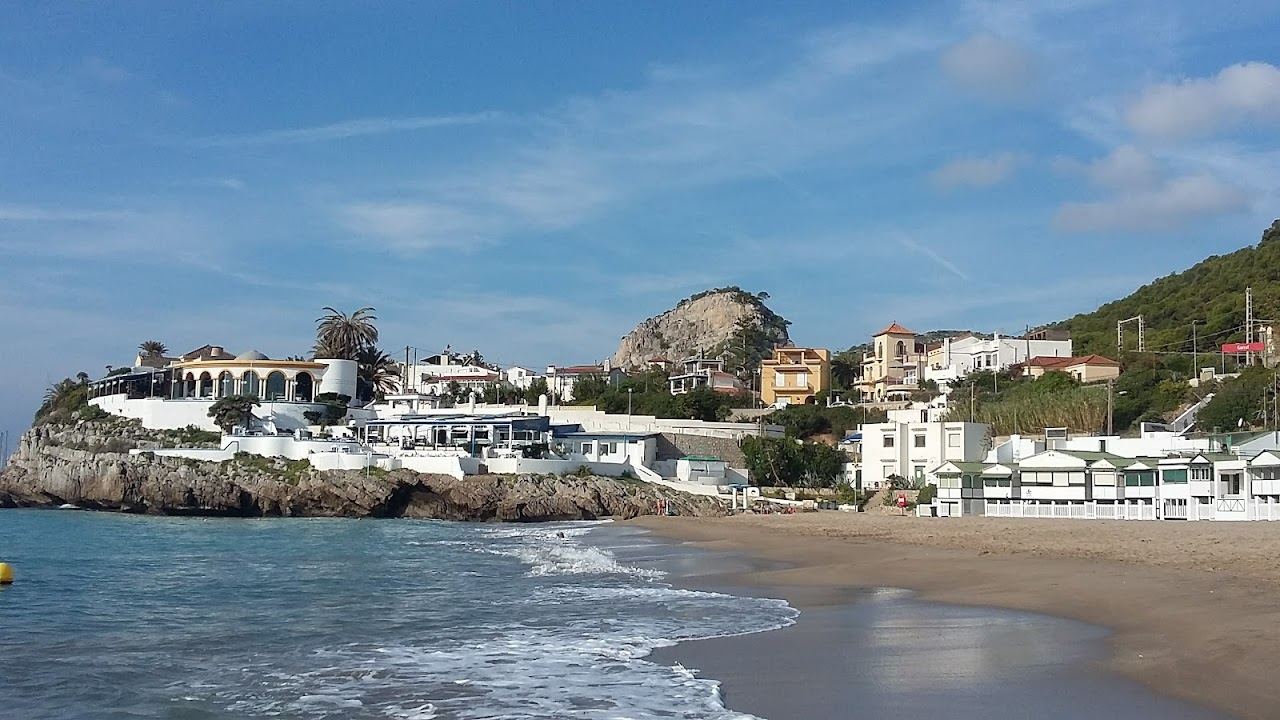 A small cove of sand with quaint striped beach huts below cliffs at Garraf near Barcelona