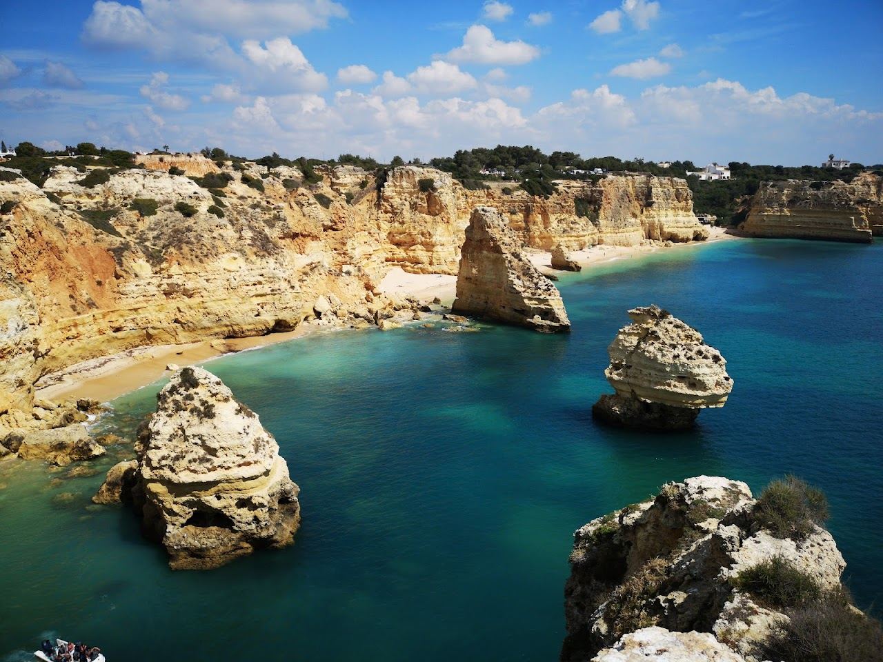 Golden limestone cliffs, sea stacks and clear green water at Praia da Marinha in the Algarve, Portugal