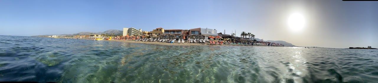 The long sandy resort beach and blue water at Malia on the north coast of Crete