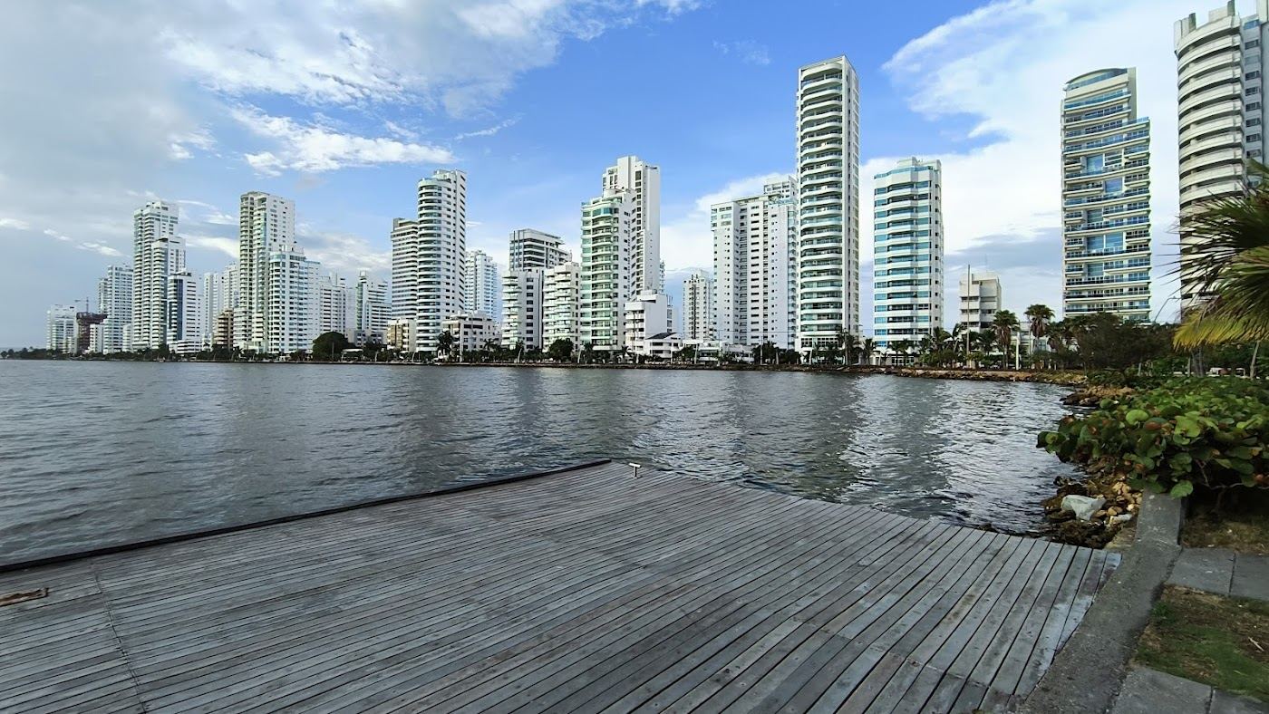 Umbrellas and vendors along the grey sand of Bocagrande beach beneath the Cartagena skyline