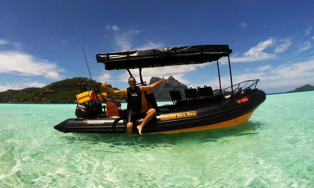 Snorkellers in the clear turquoise lagoon around a small motu in Bora Bora