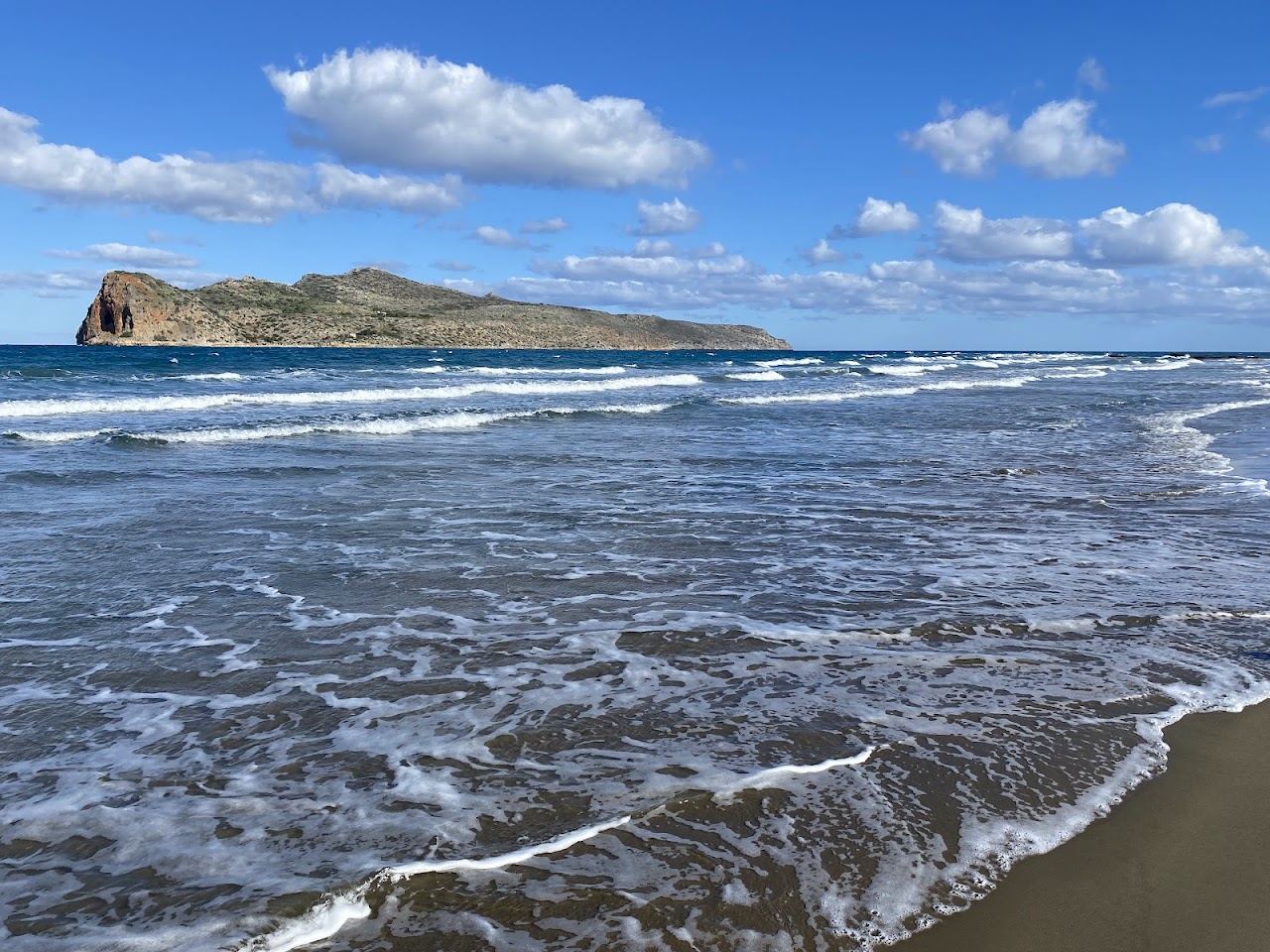 Long sandy shoreline and clear shallow water at Agia Marina beach west of Chania