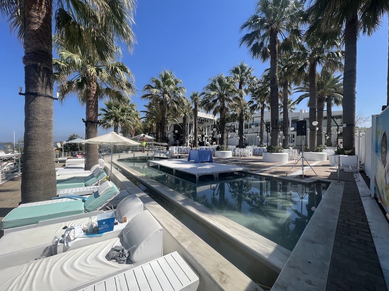 Sunbeds and palm trees on the sand at Cabana Mare Beach Club on Agia Marina beach in Crete