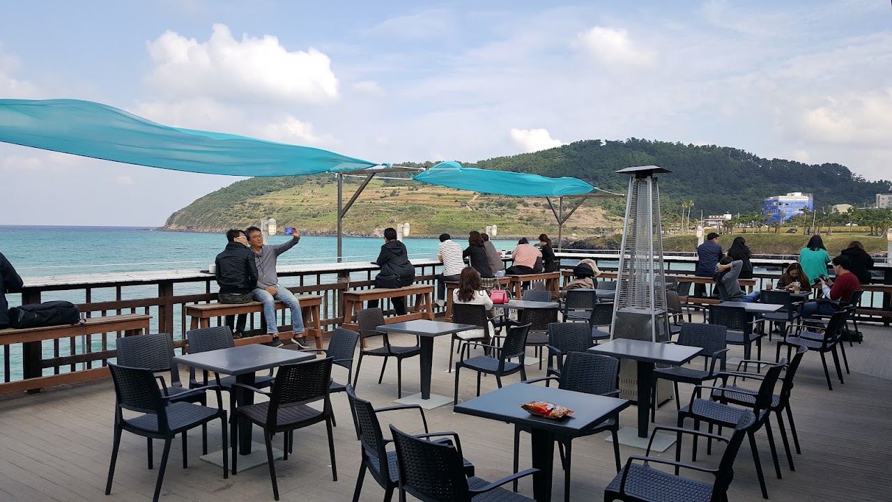 Glass fronted floors of Cafe Del Moondo rising directly above the sand at Hamdeok Beach in Jeju