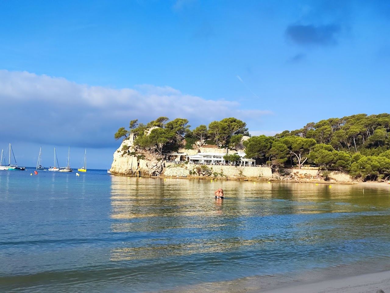 Calm turquoise water and pale sand ringed by pine cliffs in the Cala Galdana horseshoe bay Menorca