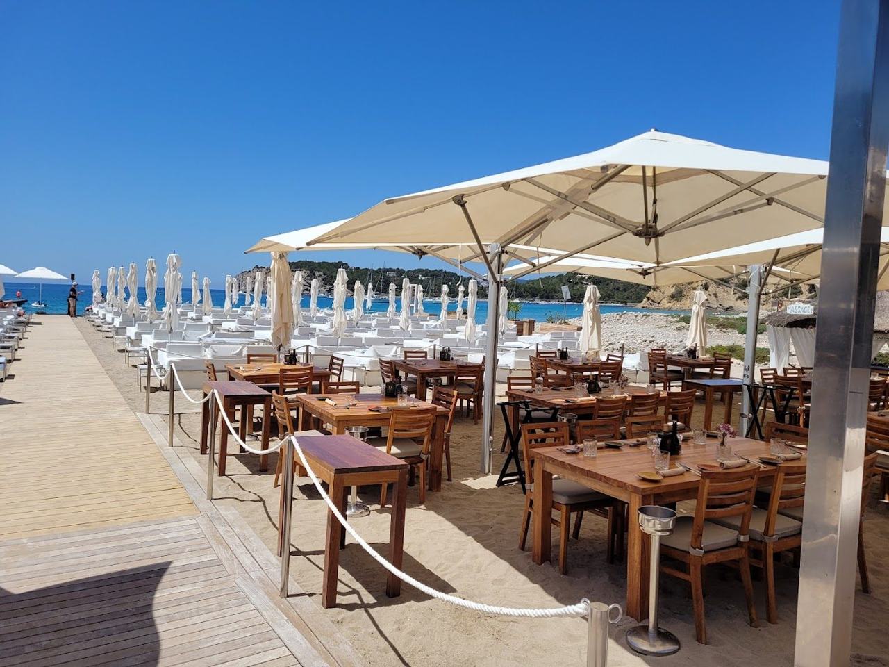 Daybeds and a beach club above the smooth pebbles of Cala Jondal in southern Ibiza