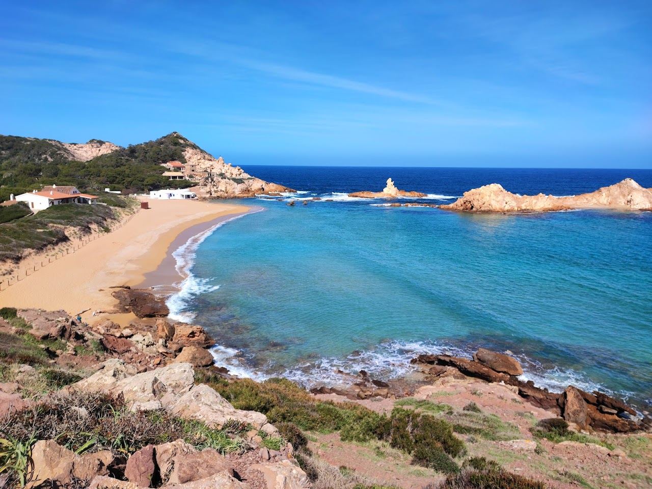 Red sand and volcanic rock stacks in the wild bay of Cala Pregonda on the north coast of Menorca
