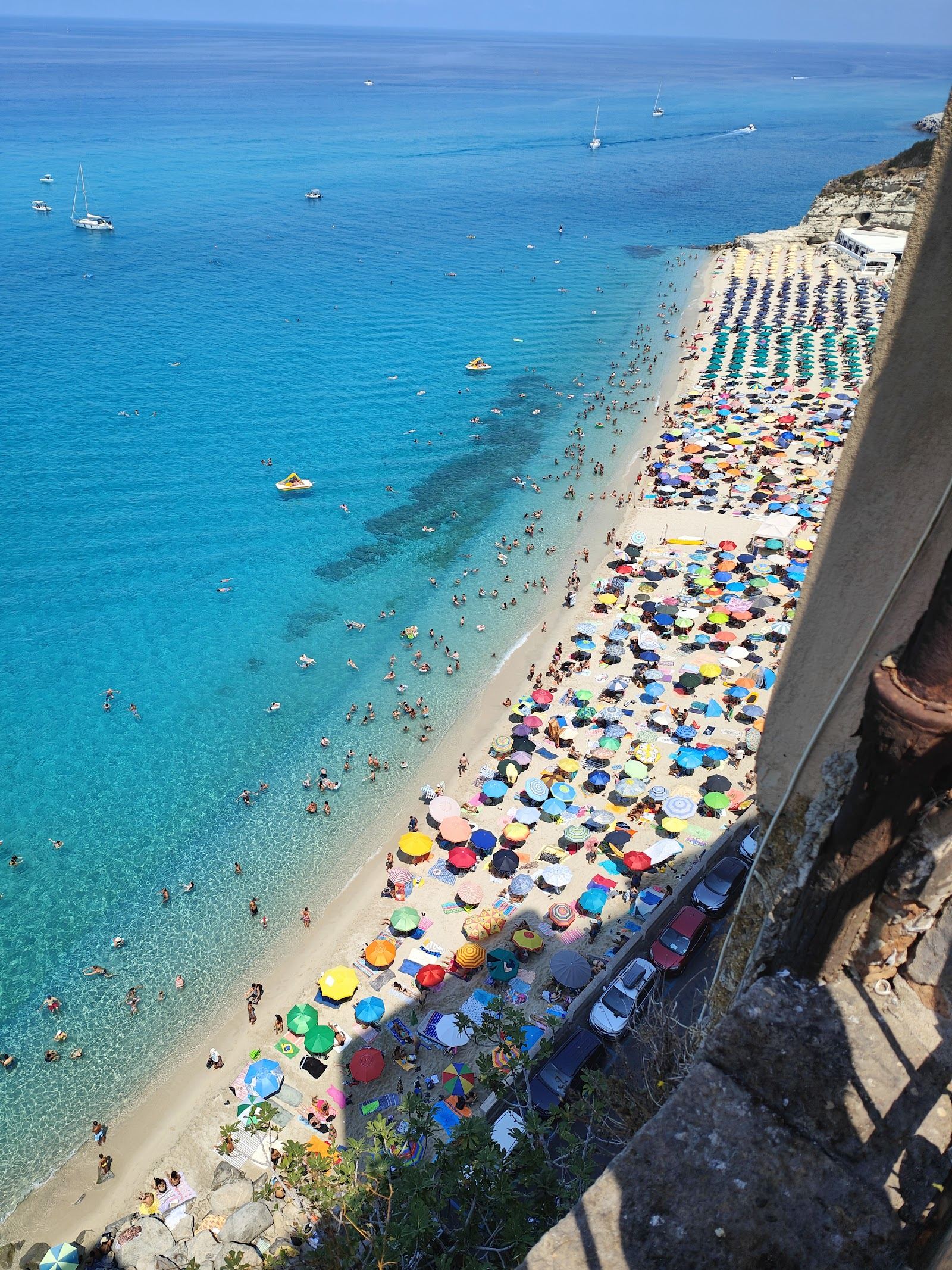 Turquoise water and free public sand below the cliff town of Tropea in Calabria