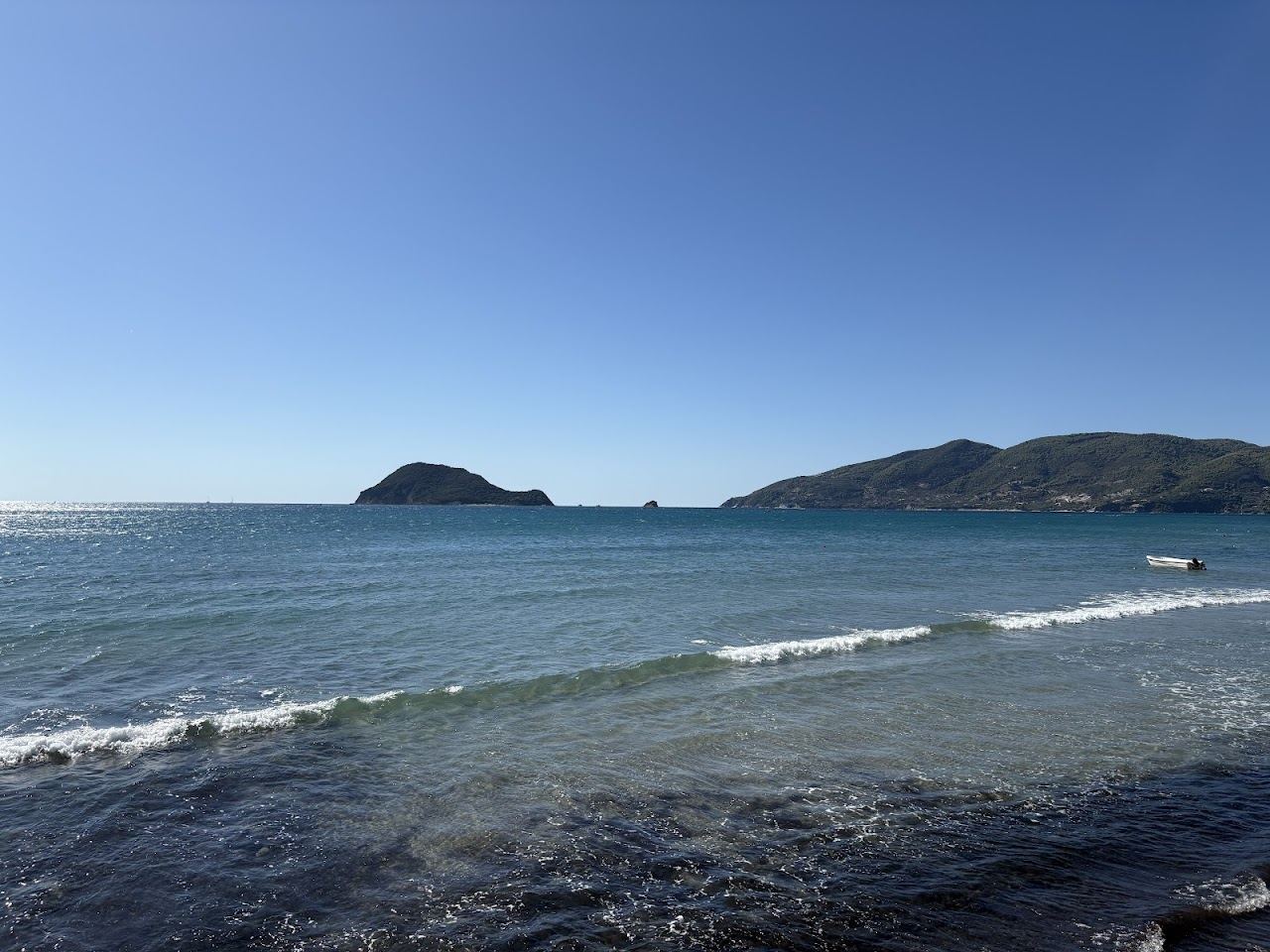 Clear shallow water and small boats at Agios Sostis harbour beside Cameo Island on Zakynthos