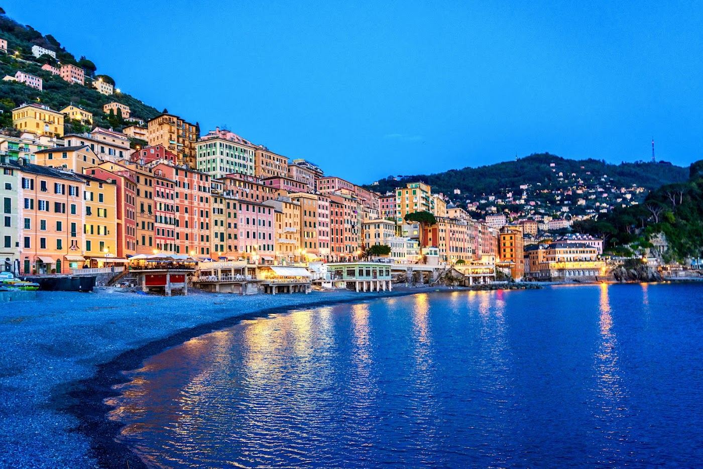 The tall painted houses and harbour of Camogli above its shingle beach in Liguria