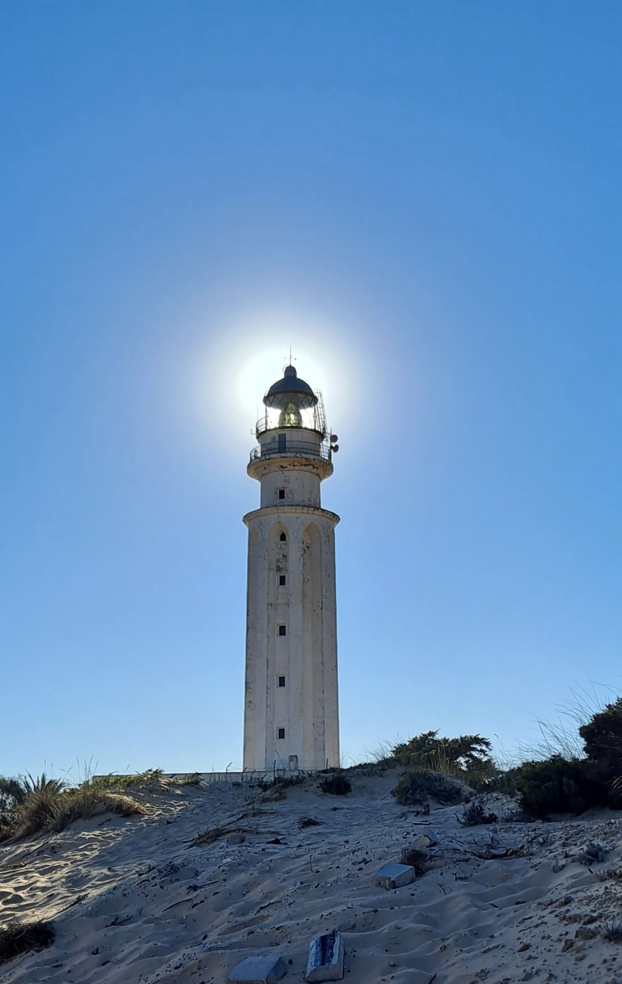 The whitewashed Faro de Trafalgar lighthouse on its sandy spit beside Canos de Meca beach at golden hour