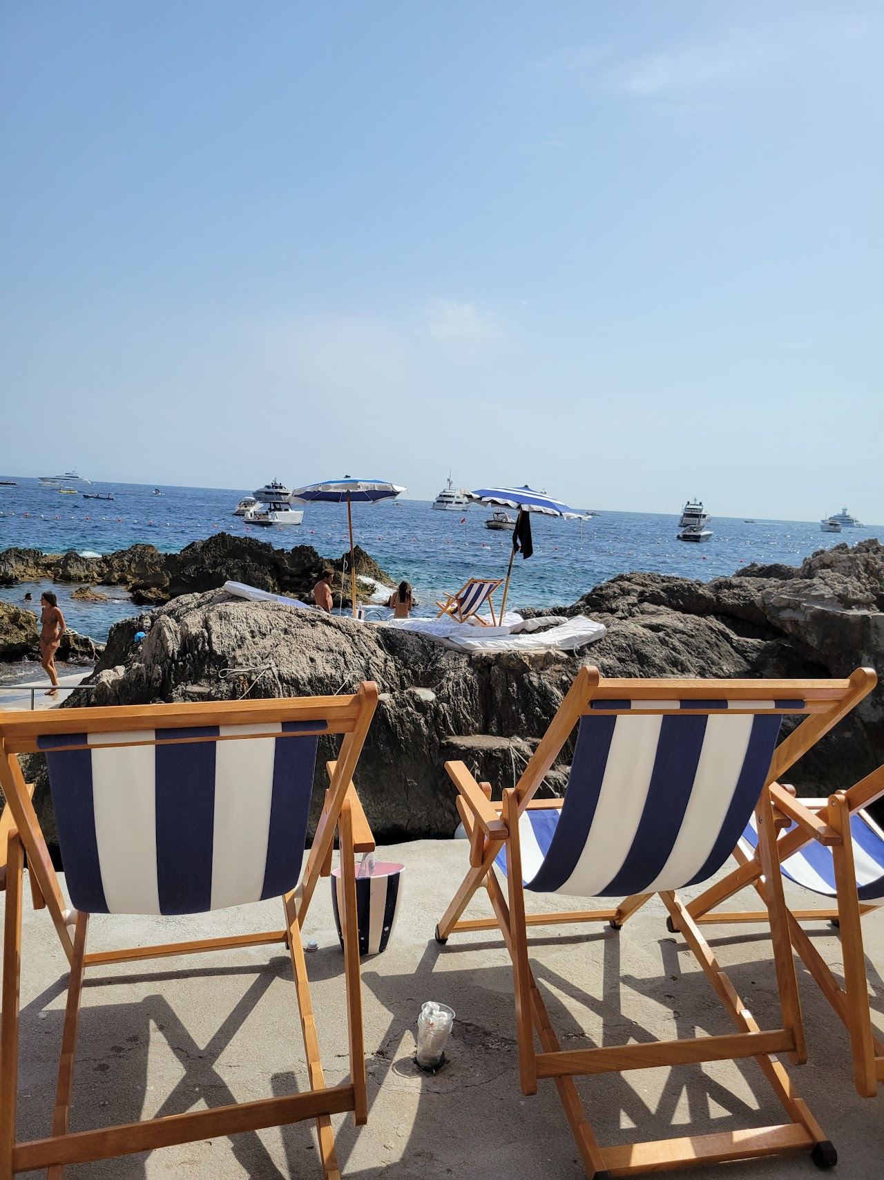 Sun loungers on the rocks at a Capri beach club below the Faraglioni