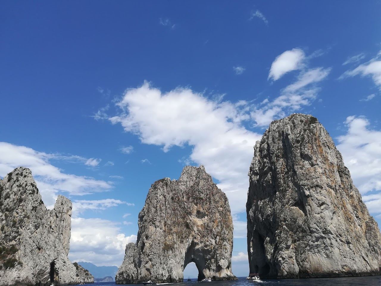 The Faraglioni rocks rising from clear blue water off Capri on a calm day