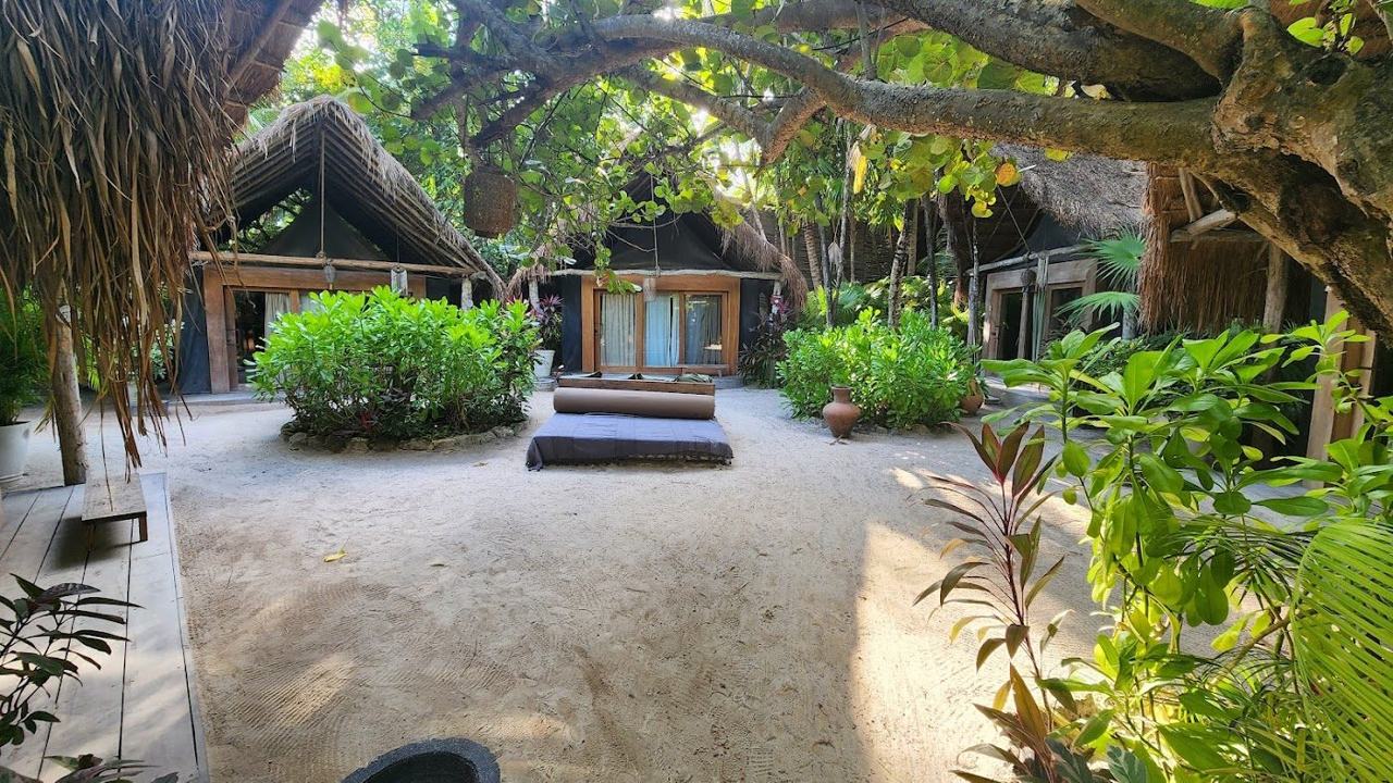 A bohemian beach club with daybeds and macrame shades on the white sand at Tulum