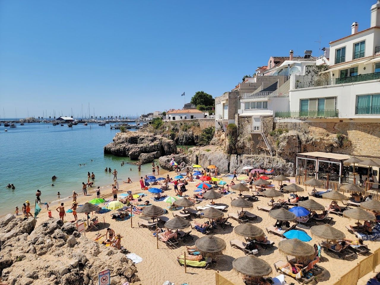 Sheltered clear water and golden sand below the town at Praia da Rainha in Cascais