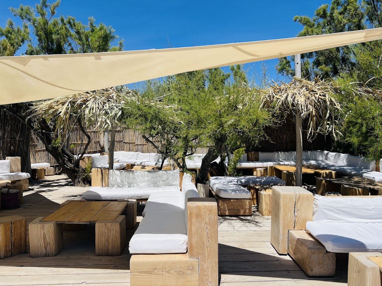 White parasols and simple sunbeds on the sand in front of Le Club 55 on Pampelonne beach, Ramatuelle