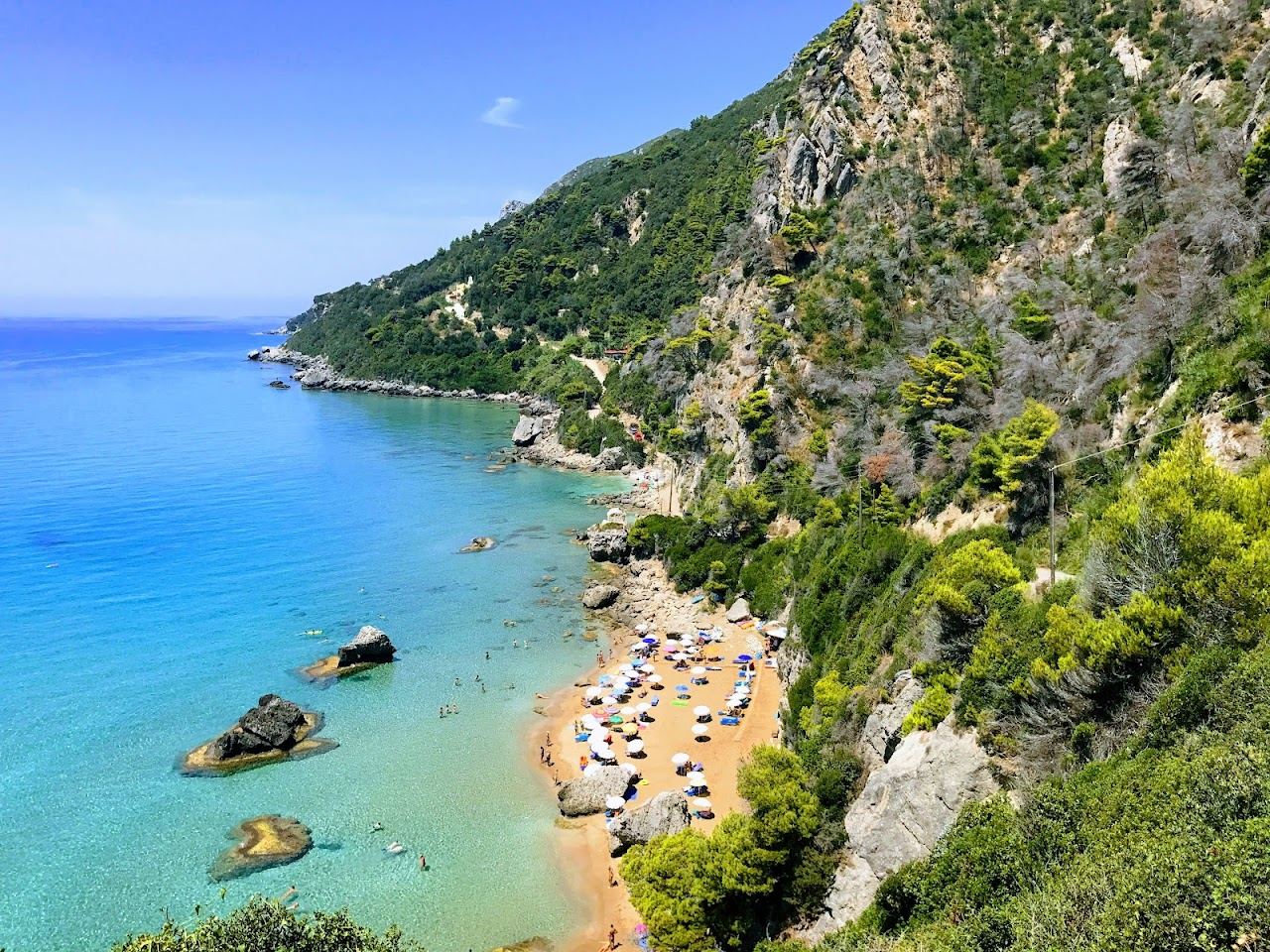 Pale sand and turquoise water below green cliffs at Myrtiotissa on the west coast of Corfu