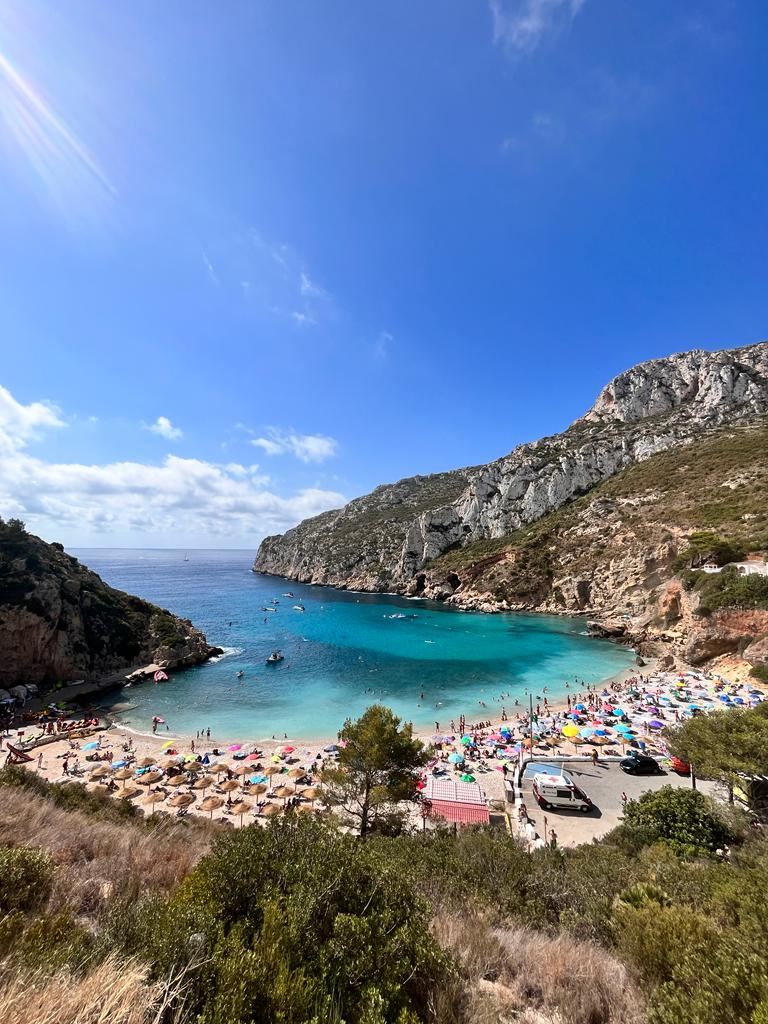 Clear turquoise water and a pebble cove backed by pines at Cala Granadella near Javea on the Costa Blanca