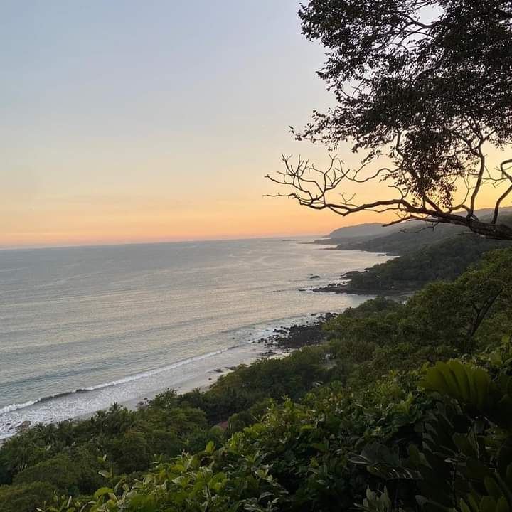 A wide surf beach at golden hour with a relaxed crowd at Santa Teresa in Costa Rica