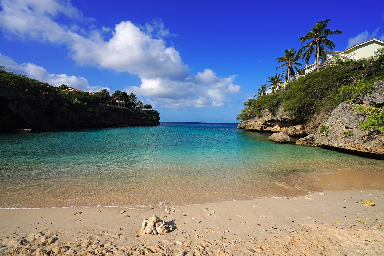 A quiet cliff framed cove on the Banda Abou coast of Curacao with clear turquoise water